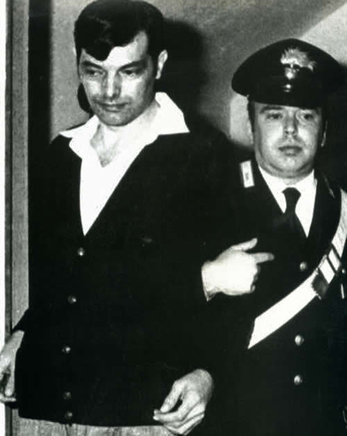Gianfranco Stevanin viene condotto in aula. Si noti la folta capigliatura che copre la cicatrice. (Foto AP Nica)